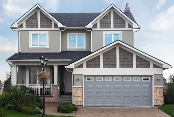 New two-storied gray brick cottage with garage on first floor.