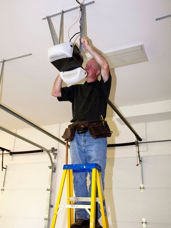 A garage door technician is working on a garage door opener. 