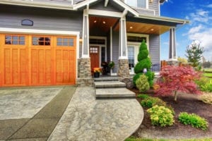 Luxury house entrance porch with stone column trim. View of walkway with landscape
